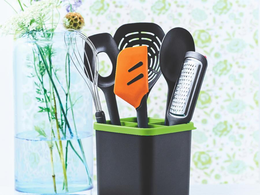 mixed tupperware utensils sitting on a counter with flower wallpaper